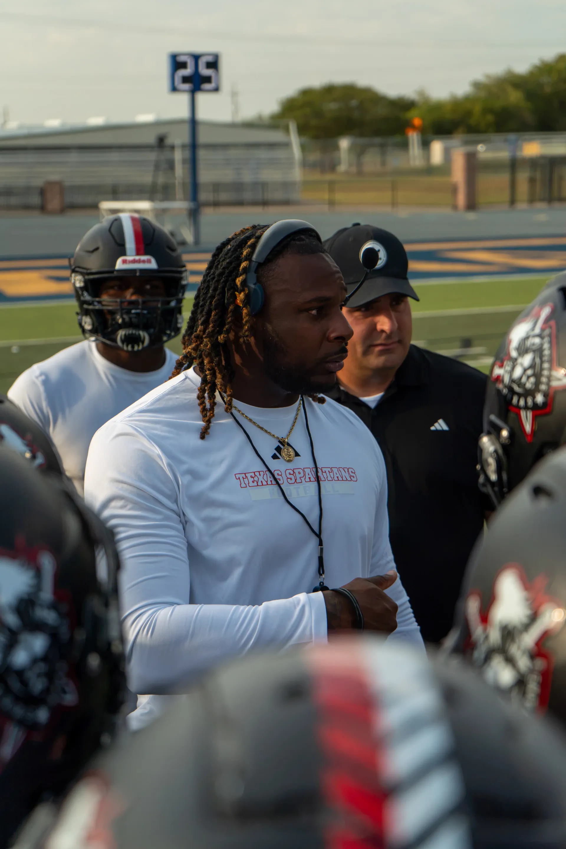 Coach Darnell Newman on the sideline in a headset with his players during a game