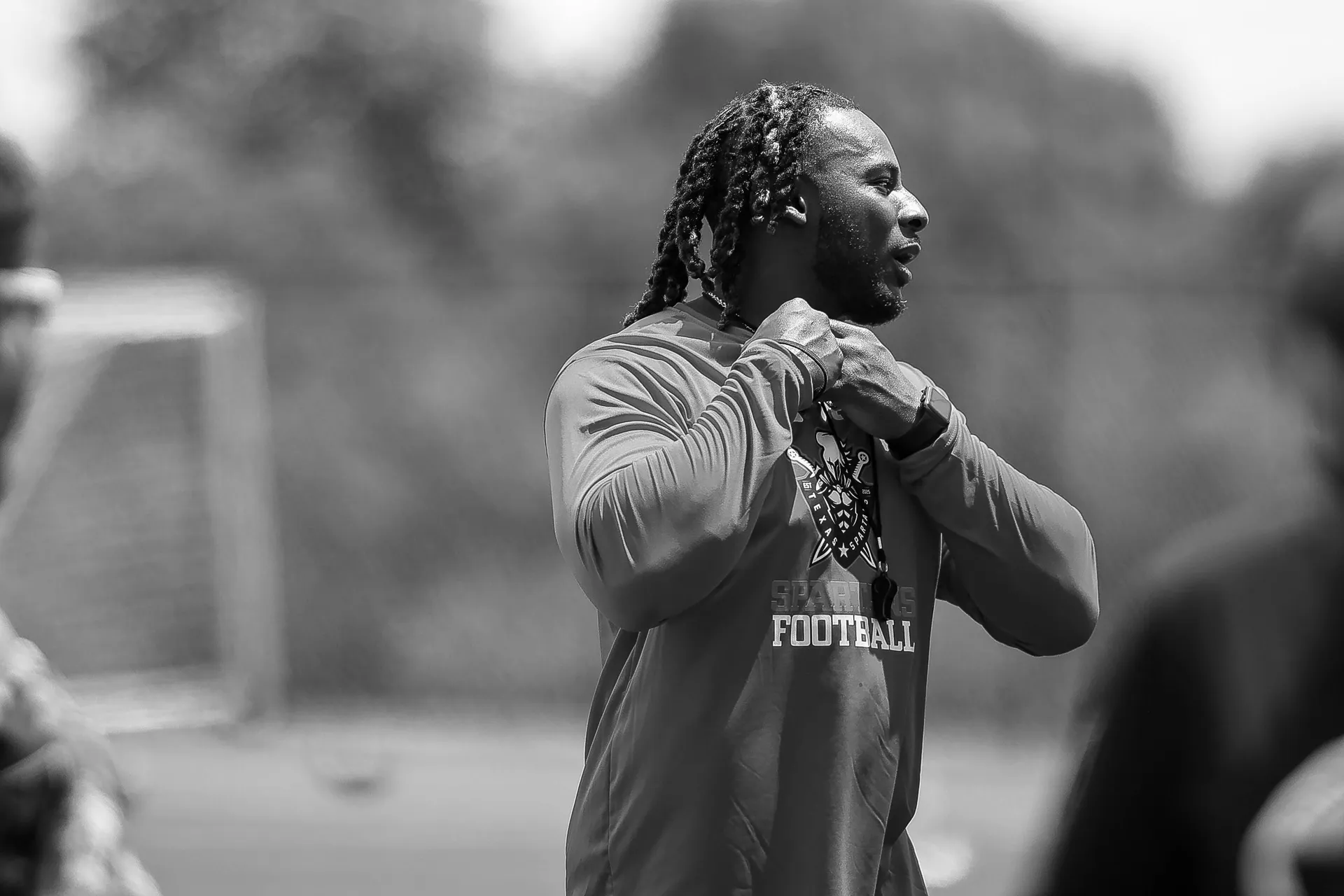 Coach Darnell Newman walking across the football field with his team behind him