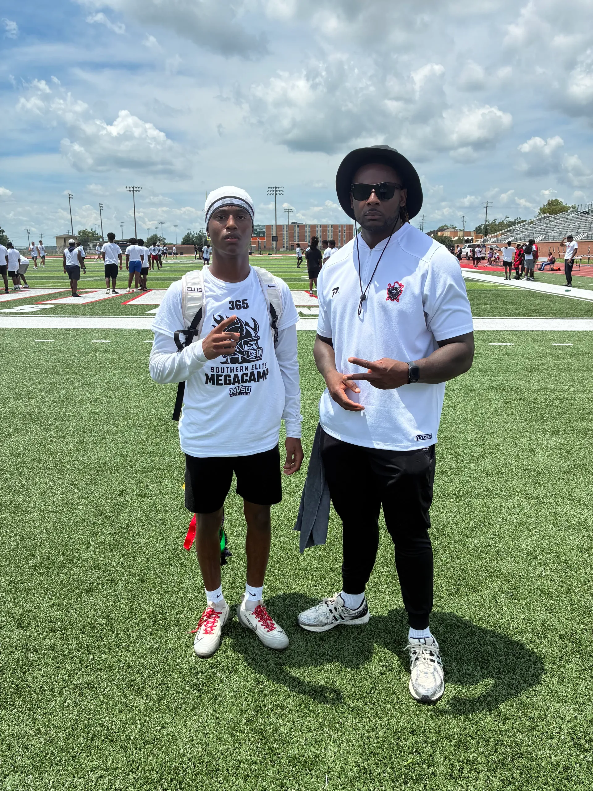 Coach Darnell Newman with a recruit wearing a Southern Elite Mega Camp shirt on a college practice field